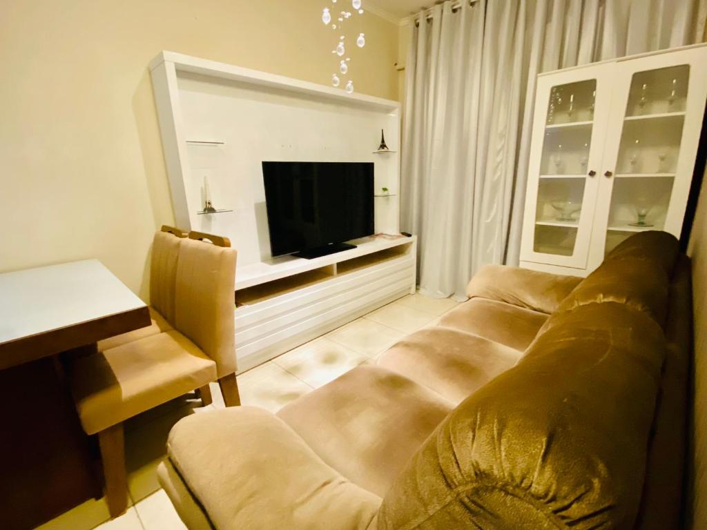 een woonkamer met een bank en een televisie bij Mega Flat na Praia da Ocian - Praia Grande in Praia Grande