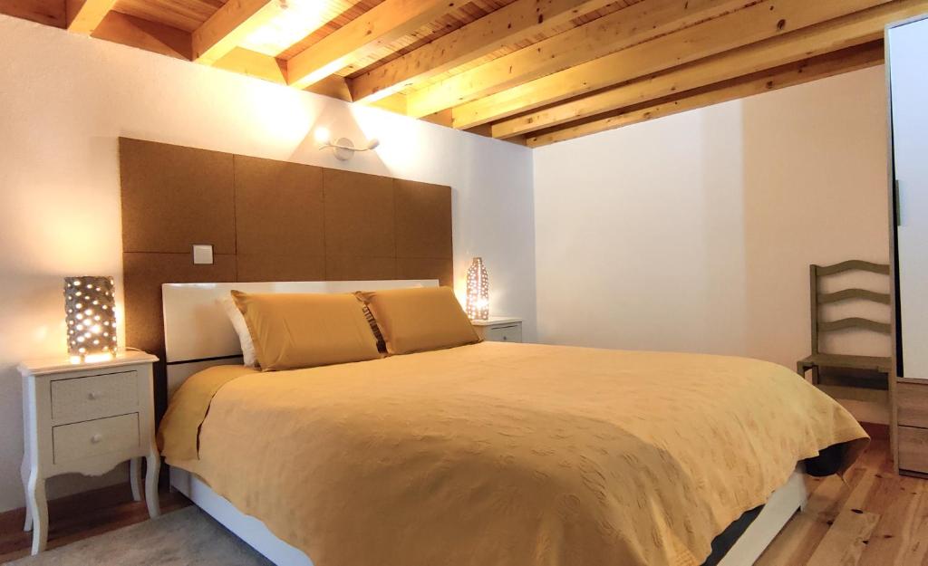 a bedroom with a large bed and wooden ceilings at Casa Rural d 'Avó - sossego do campo - 5 adultos in Alhais