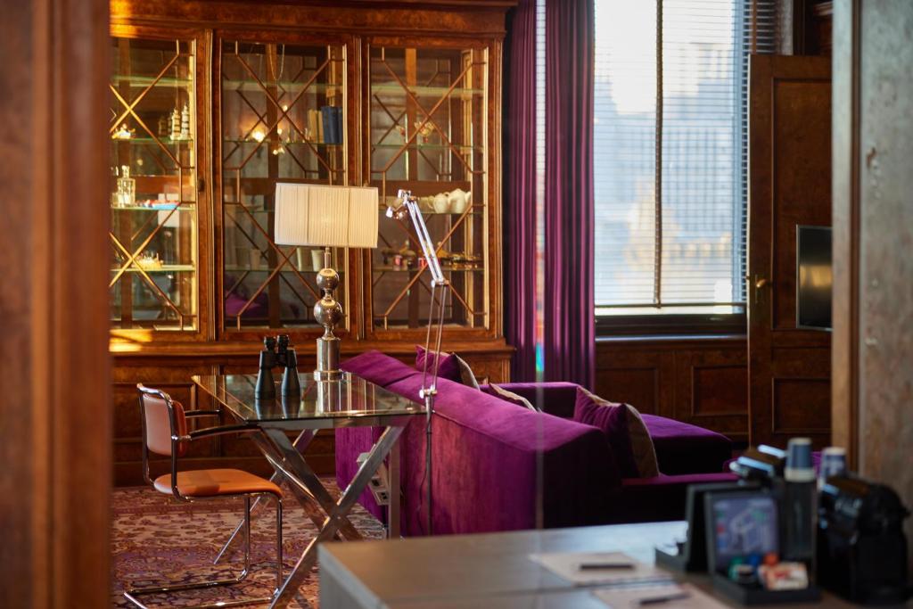 a room with a desk and a table with a lamp at Hotel New York by WestCord in Rotterdam