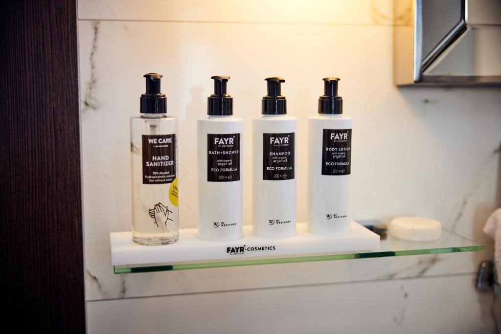 a shelf with four bottles of hair products on it at Hotel New York by WestCord in Rotterdam