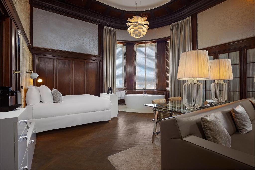 a living room with a bed and a bath tub at Hotel New York by WestCord in Rotterdam