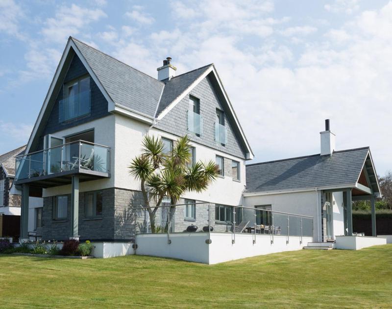 a large white house with a palm tree in front of it at Ragleighs in Polzeath