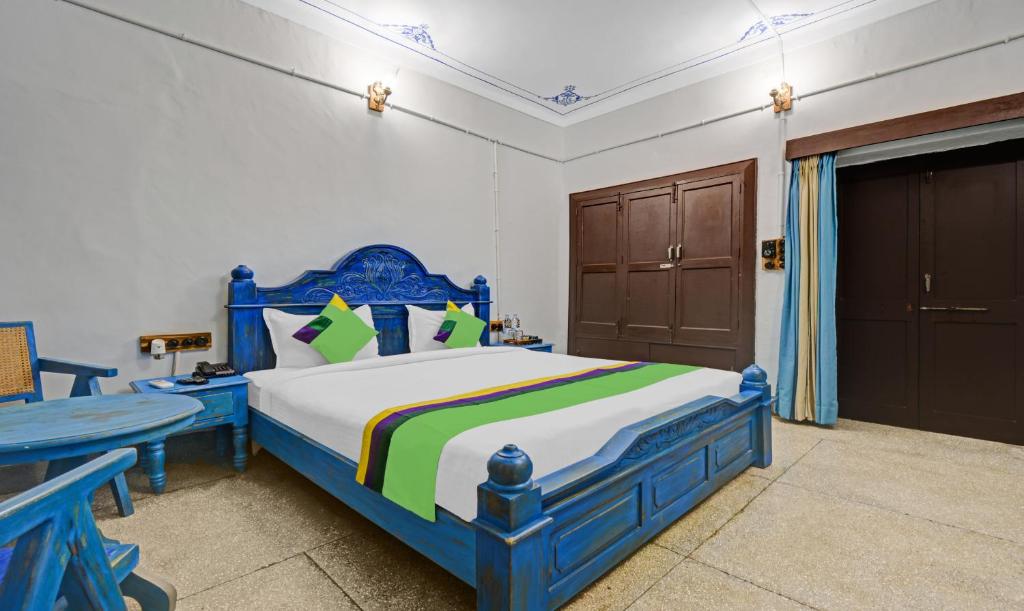 a bedroom with a blue bed and a table at Treebo Trend The Regal House 1 Km From Fateh Sagar Lake in Udaipur