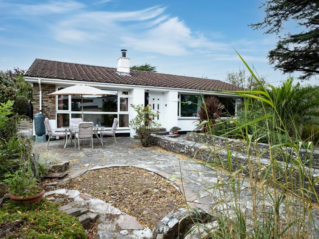 a white cottage with a patio and an umbrella at Longhouse Bungalow in Polzeath