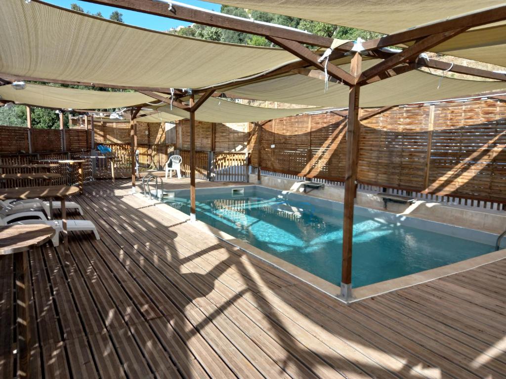 ein Swimmingpool unter einem Sonnenschirm auf einer Holzterrasse in der Unterkunft Ducourneau Grimaldi in Moltifao