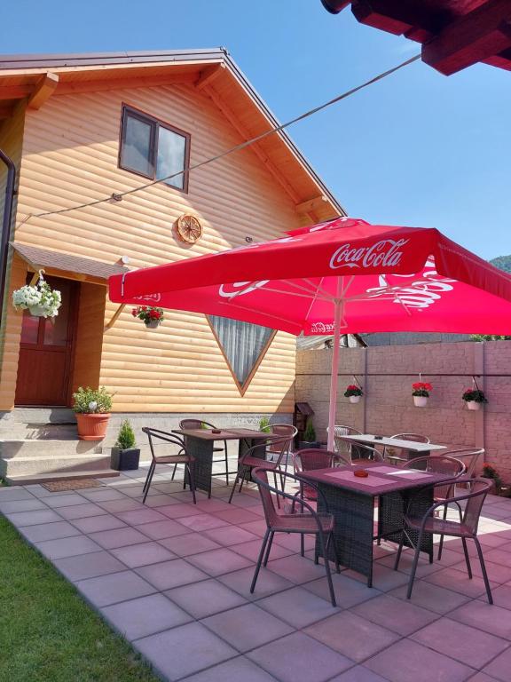 d'une terrasse avec des tables, des chaises et un parasol rouge. dans l'établissement Cabana Rustica Georgeta, à Zărneşti
