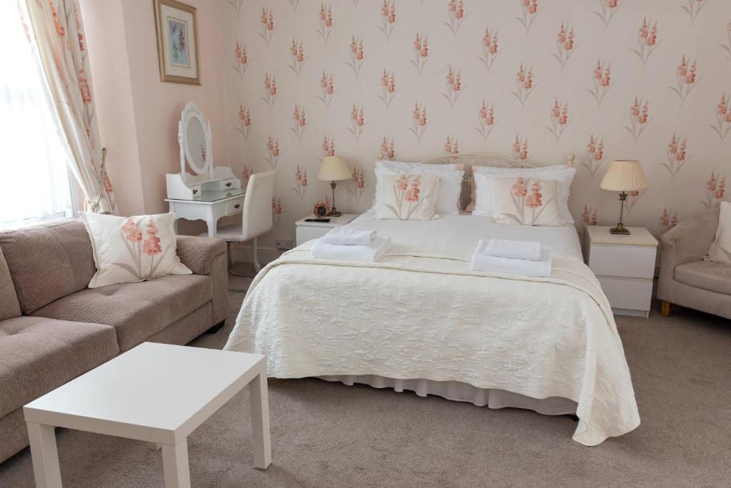 a bedroom with a white bed and a couch at Rosita Guest House in Weston-super-Mare