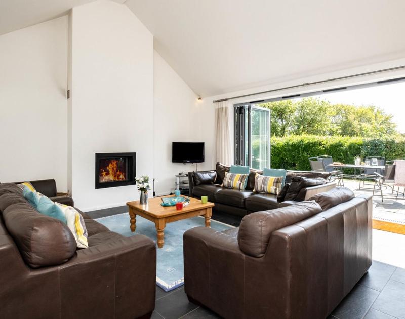 a living room with leather couches and a fireplace at Lerryn in Saint Minver