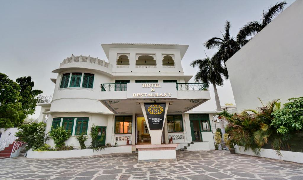 a white building with a palm tree in front of it at Treebo Trend The Regal House 1 Km From Fateh Sagar Lake in Udaipur