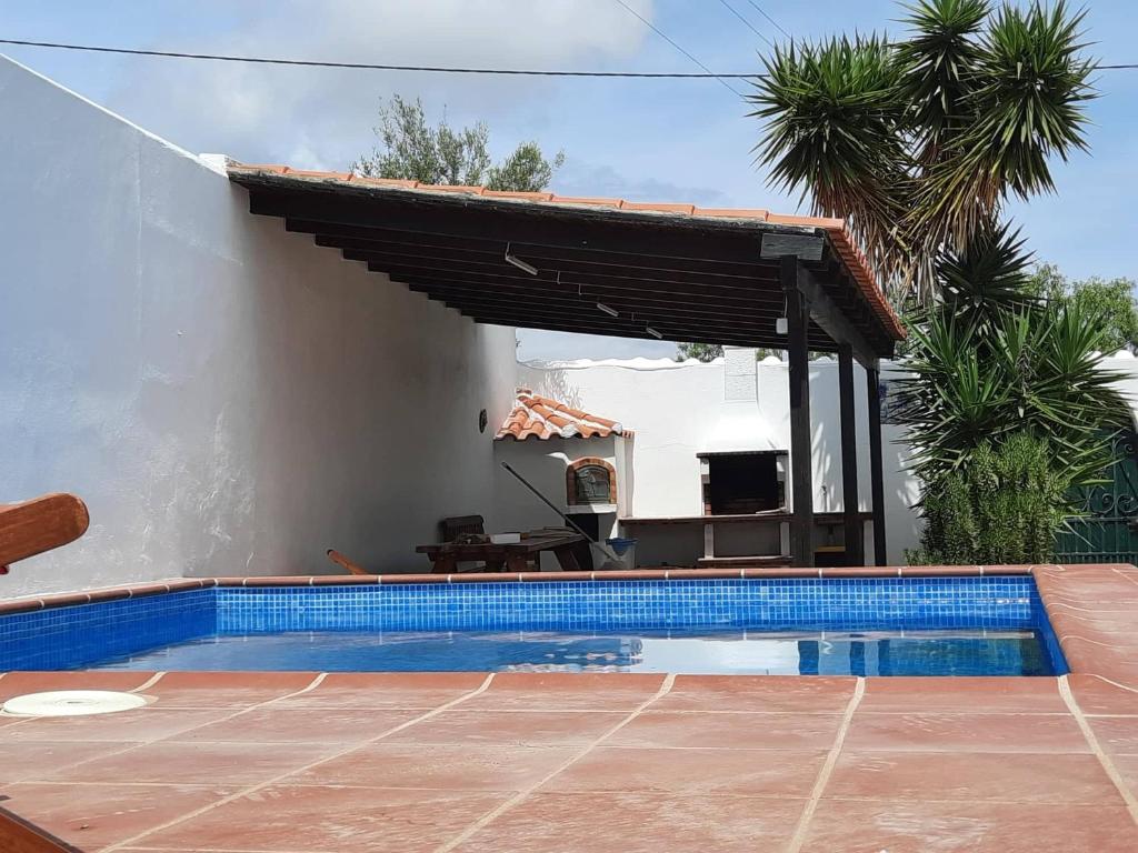 a swimming pool in front of a house with a roof at A Casa da avó Custodinha in Bias do Norte