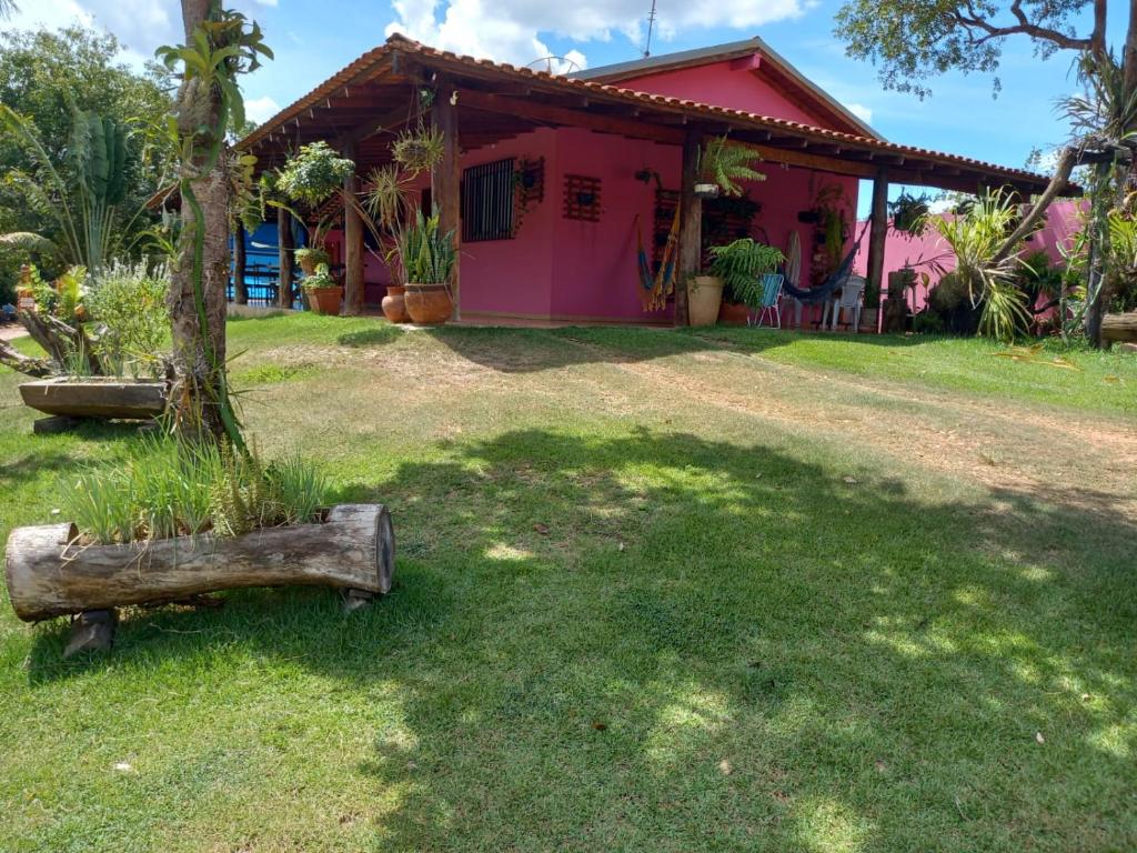 Guest House Recanto da Mata - BONITO - MS في بونيتو: منزل وردي عليه جذع شجرة