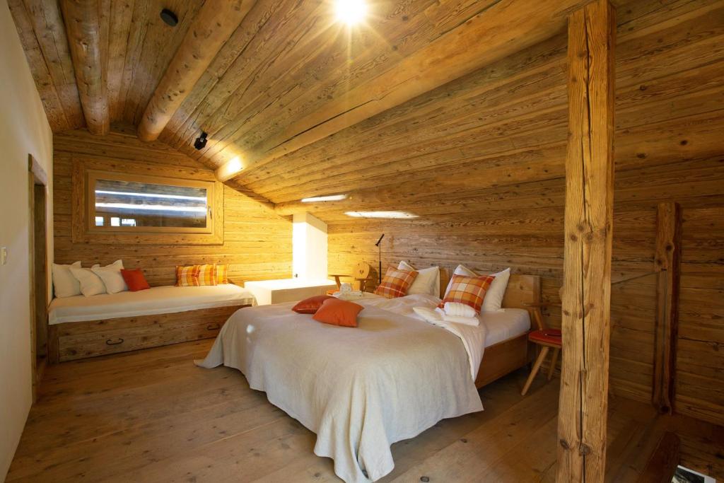 um quarto com 2 camas num chalé de madeira em Mountain Cabin Tschividains Lenzerheide em Obervaz