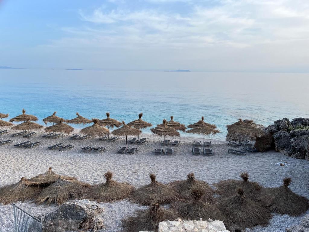 um grupo de guarda-sóis e cadeiras numa praia em White Rocks em Dhërmi