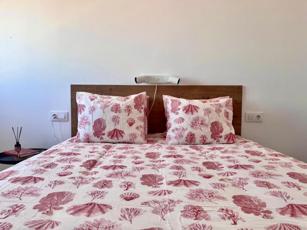a bed with pink and white sheets and pillows at GATU El Mirador de la Viña in Cádiz
