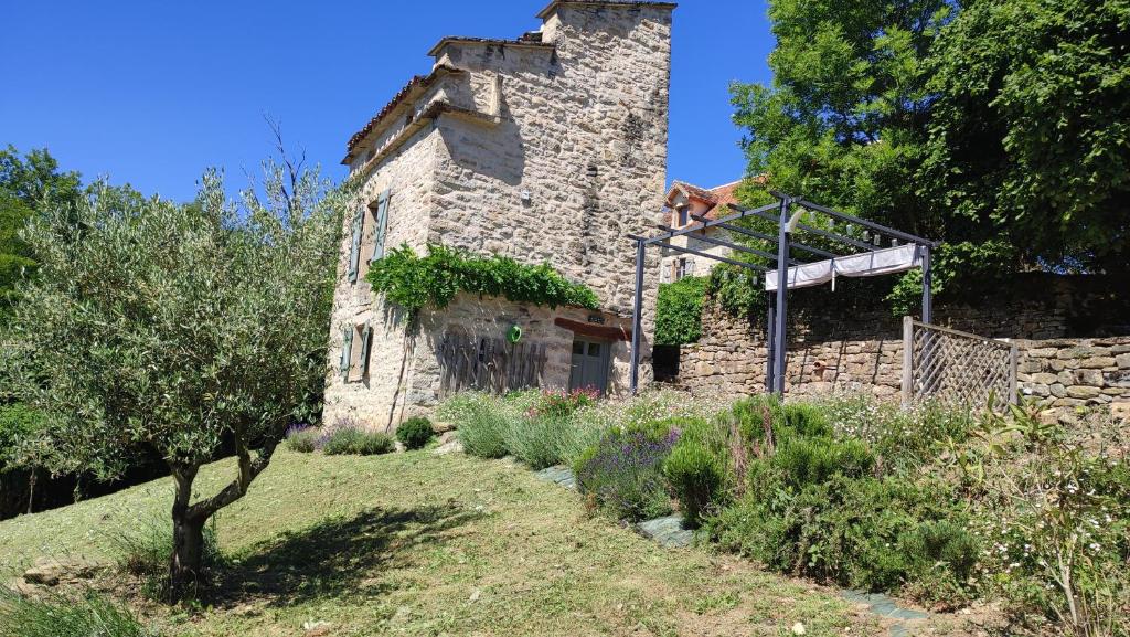 an old stone building with a tree in front of it at Le pigeonnier de felines in Caylus
