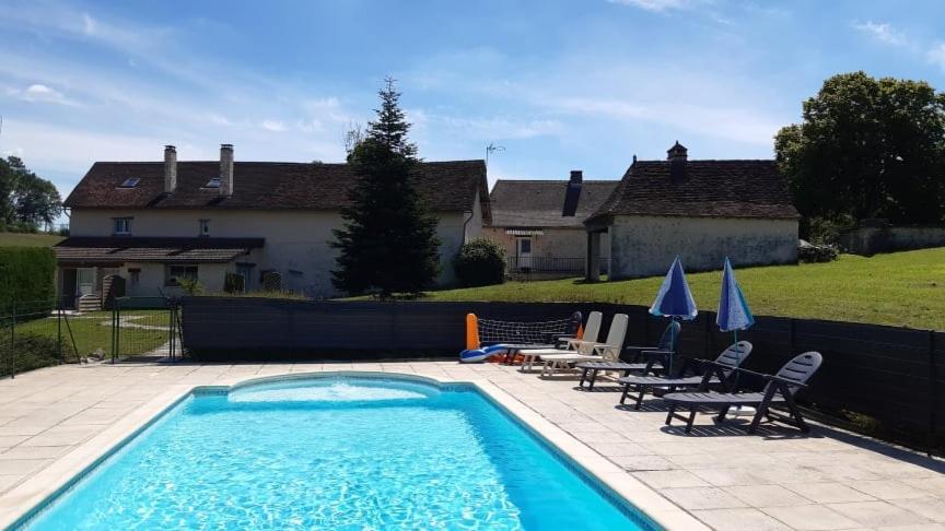 a swimming pool with chairs and umbrellas in front of a house at Gites Le Clos de Lamie avec 2 piscines privées in Fossemagne