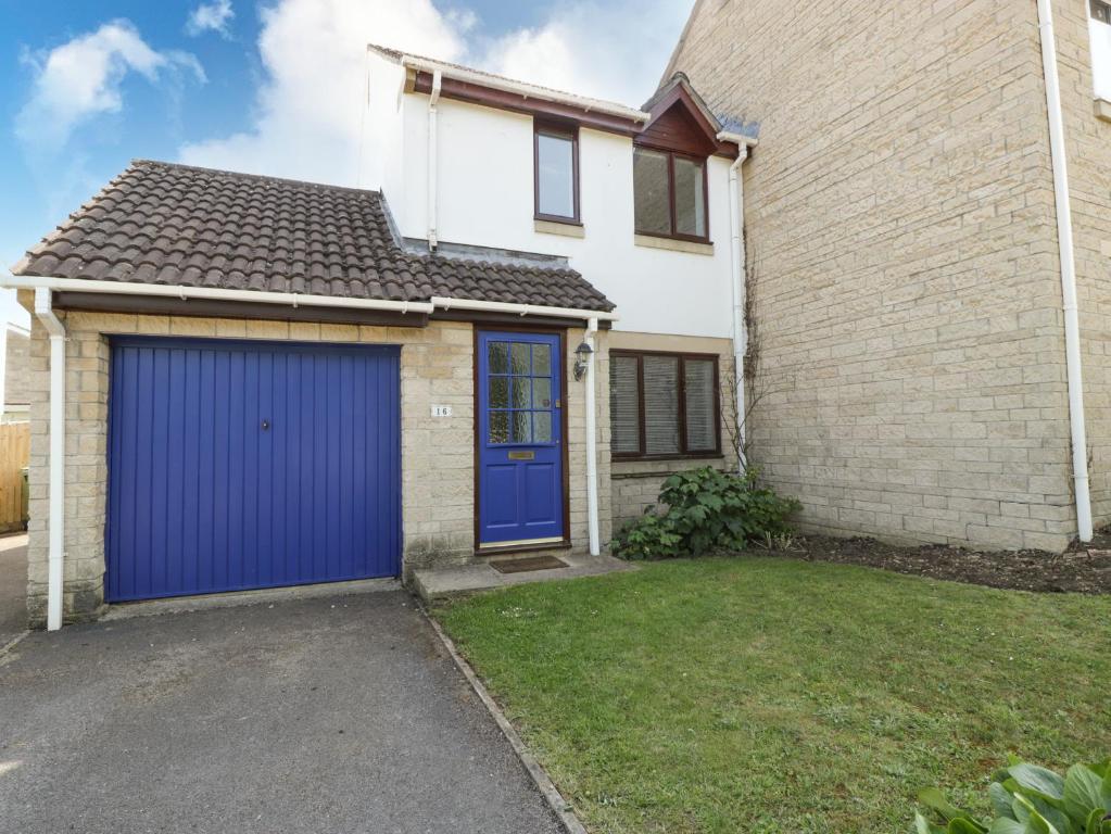 a white brick house with a blue garage at 16 Mythern Meadow in Bradford on Avon