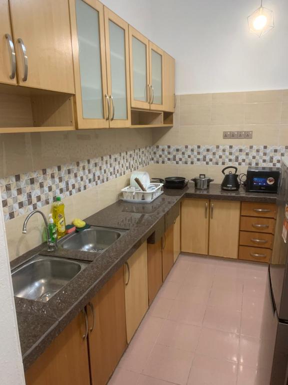 a kitchen with wooden cabinets and a sink at Queen Room Semi Attached Bathroom Bukit Mertajam Alma Impian in Bukit Mertajam