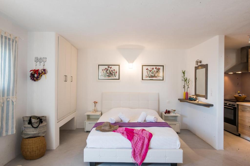 a bedroom with a white bed with a pink blanket on it at mykonos 1001 in Agios Stefanos
