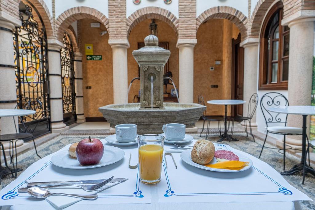 a table with apples and oranges on it with a fountain at Hotel Boutique Casa Veracruz in Estepona