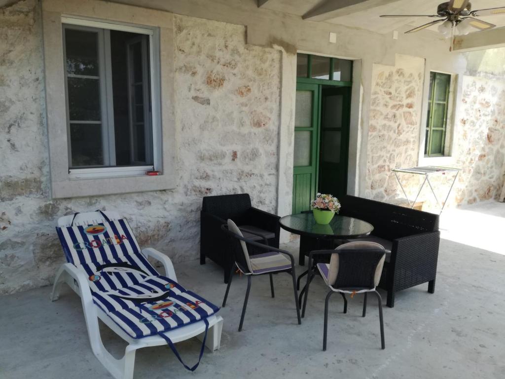 eine Terrasse mit einem Tisch, Stühlen und einer grünen Tür in der Unterkunft Kastelanic apartman in Brbinj