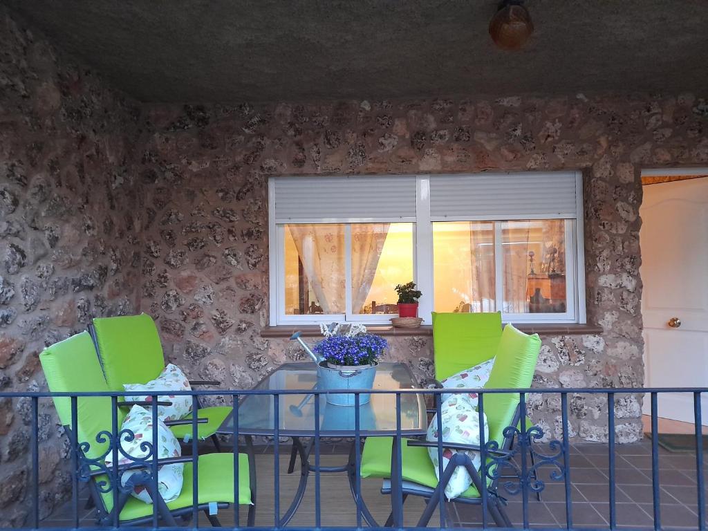 a dining room table with green chairs and a window at La casita de Riópar in Riópar