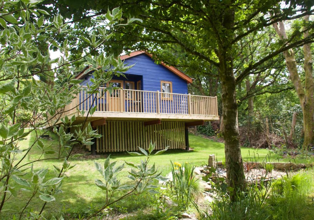 a blue house with a deck in a yard at Creekside Lodge Bathpool Launceston Cornwall in Launceston