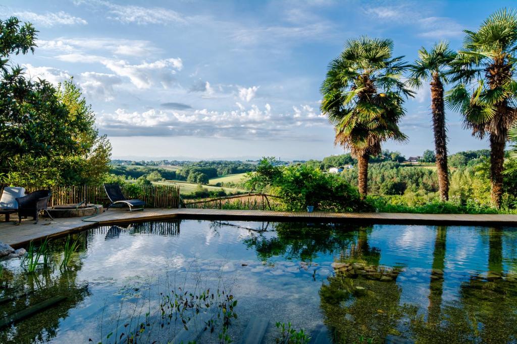 a swimming pool with palm trees in a yard at Les Chemins de Berdis in Montfort-en-Chalosse