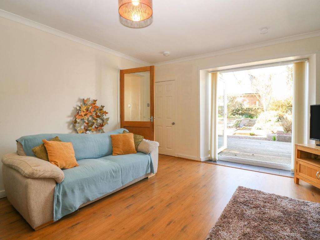 sala de estar con sofá azul y puerta corredera de cristal en Blue Skies Cottage, en Arbroath
