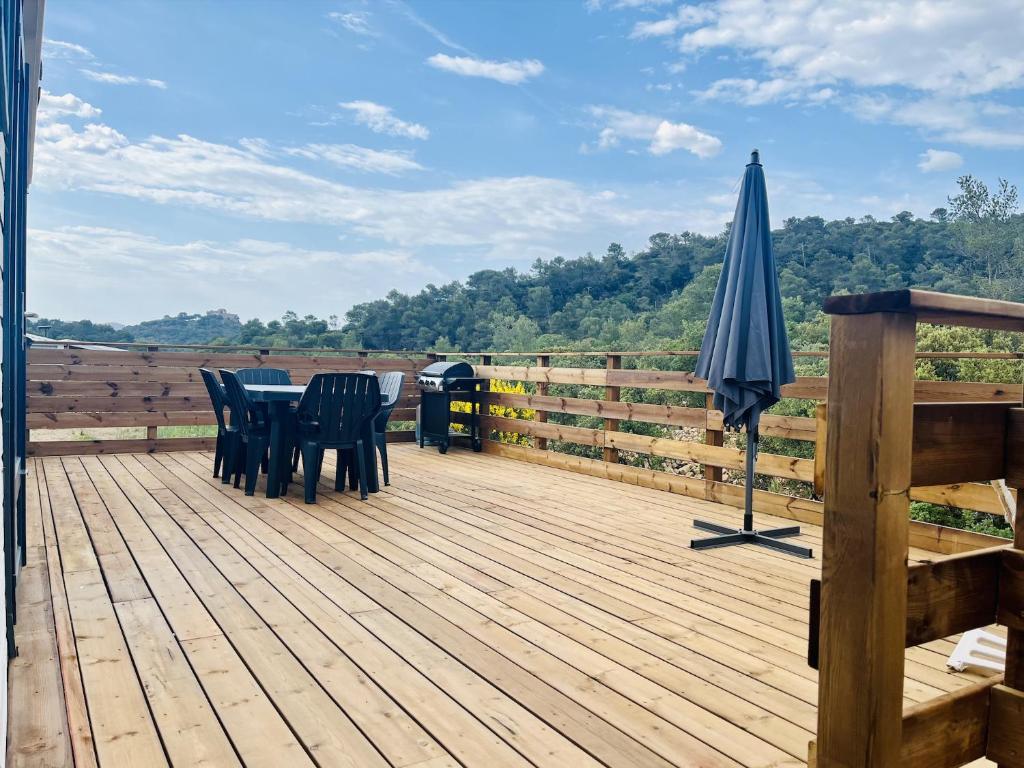 a wooden deck with a table and an umbrella at Joli Chalet avec grande terrasse et accès piscine in Rocbaron