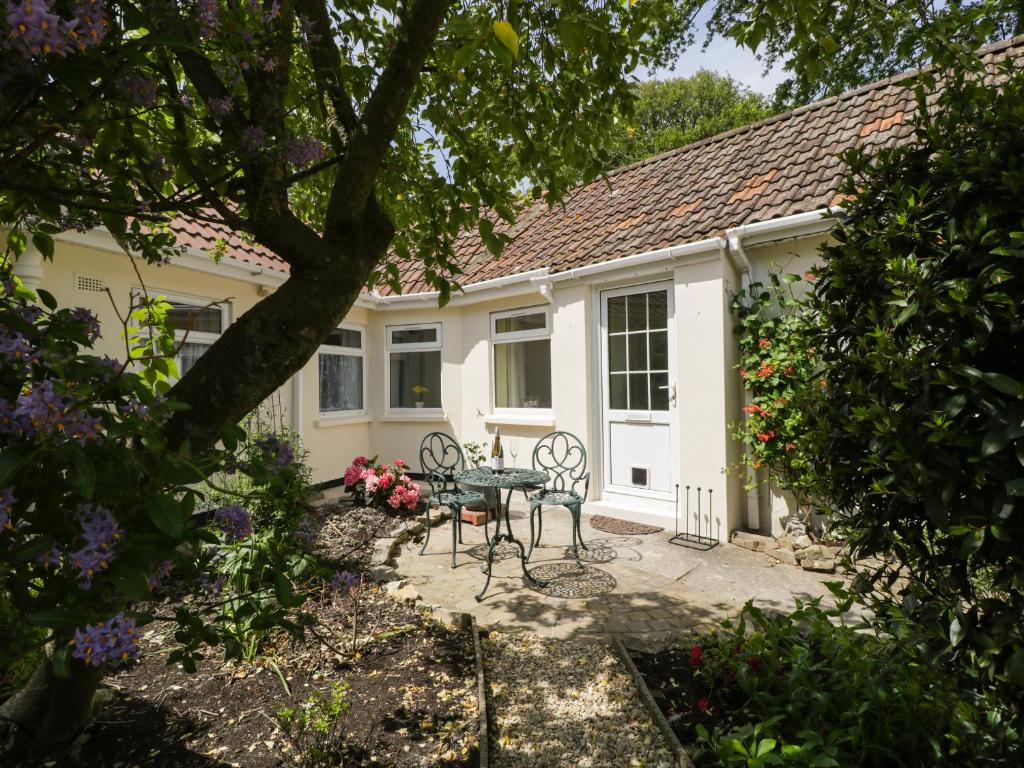 a patio with a table and chairs in front of a house at Long Batch Cottage in Shepton Mallet