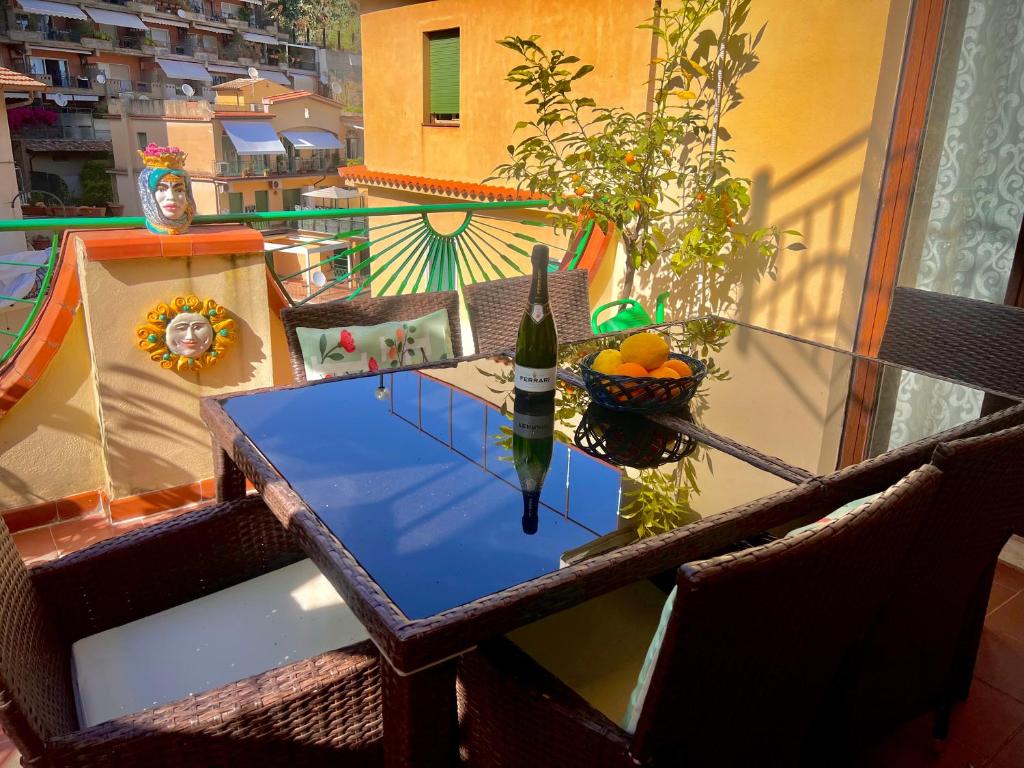 een tafel met een fles wijn en een fruitschaal op een balkon bij La Fontanella Apartment in Taormina