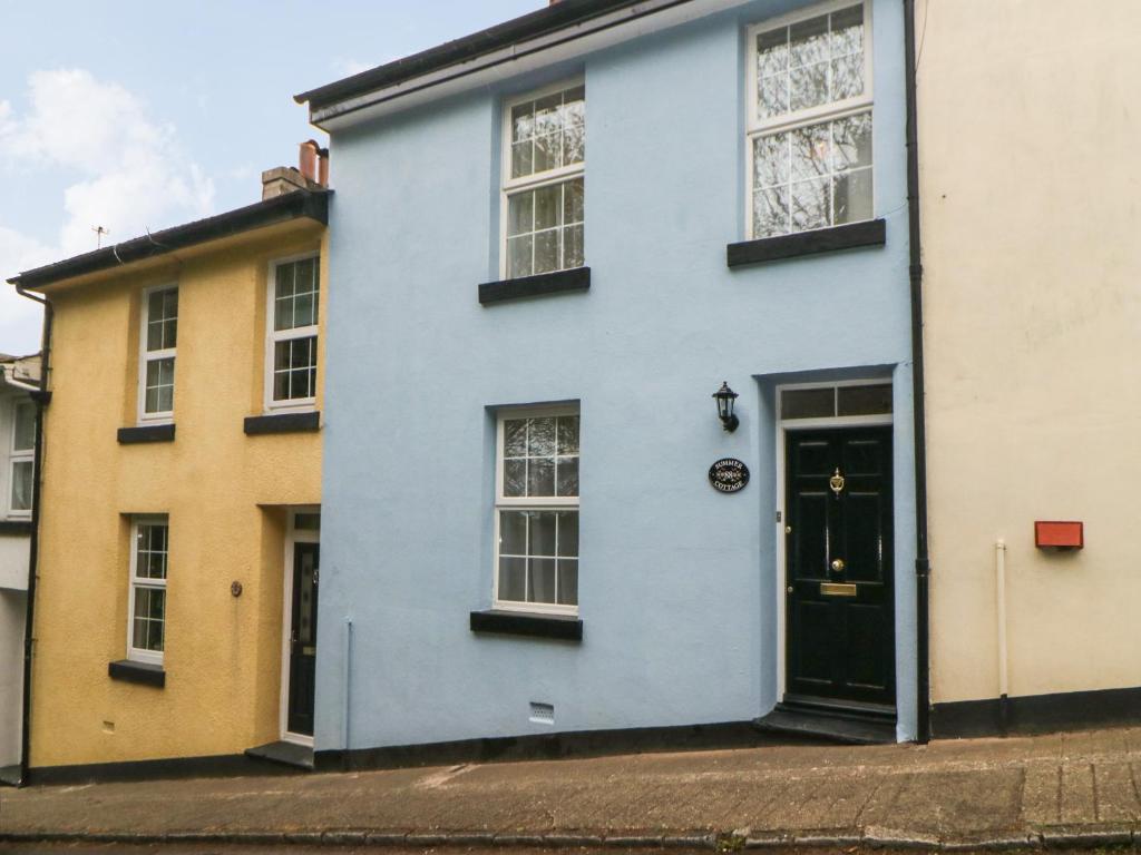 a blue house with a black door on a street at Summer Cottage in Torquay
