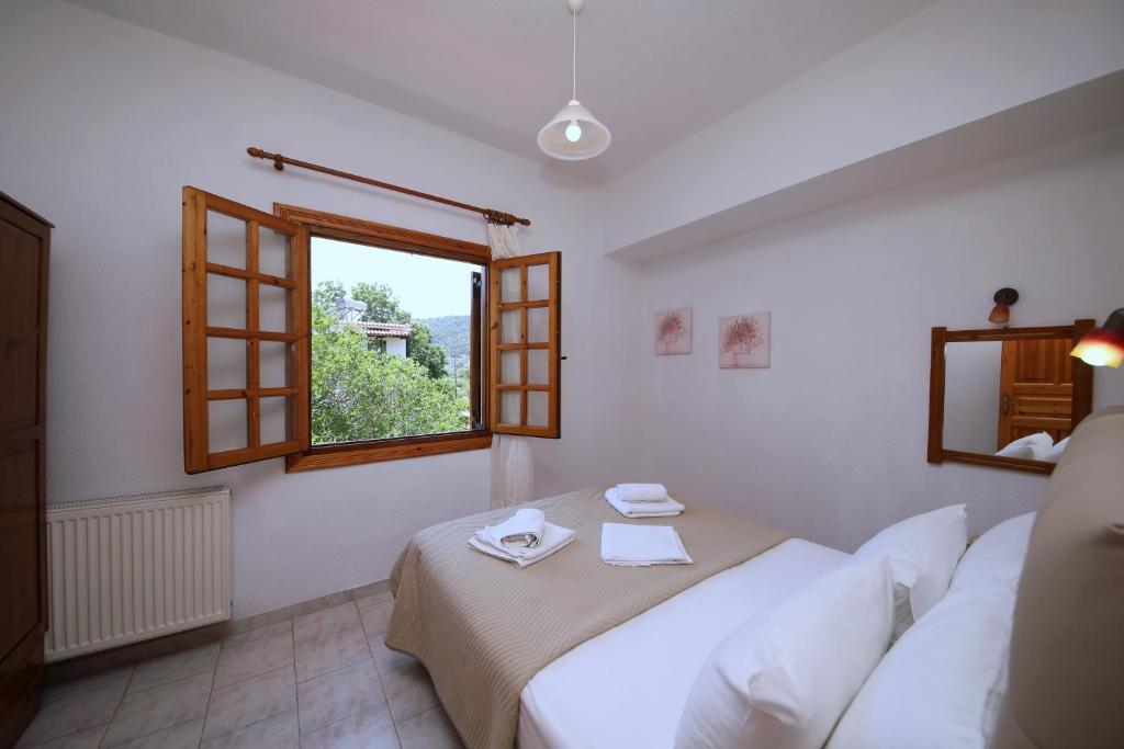 ein weißes Schlafzimmer mit einem Bett und einem Fenster in der Unterkunft Elsa Stafilos in Skopelos