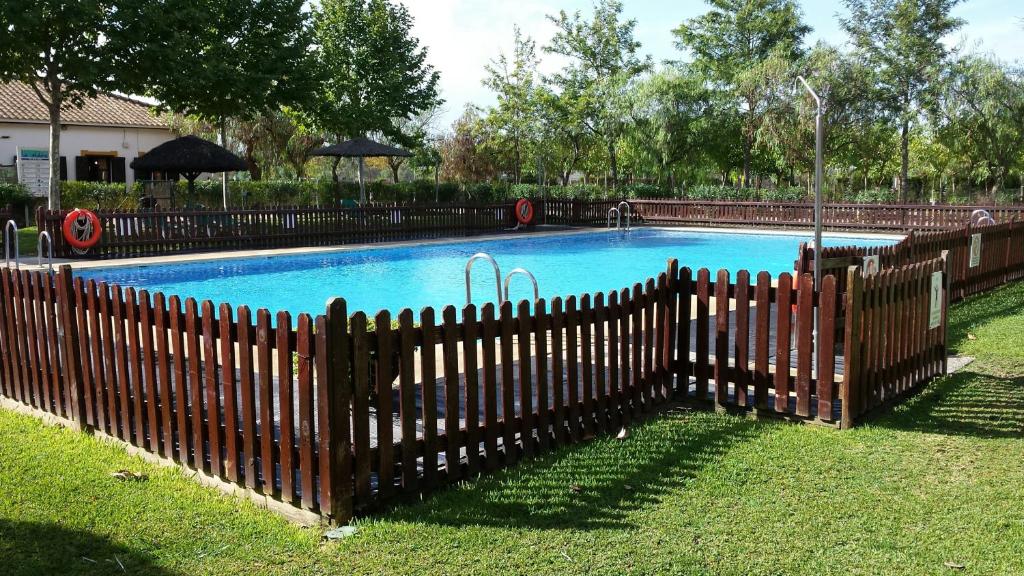 uma cerca de madeira em frente a uma piscina em Camping La Aldea em El Rocio