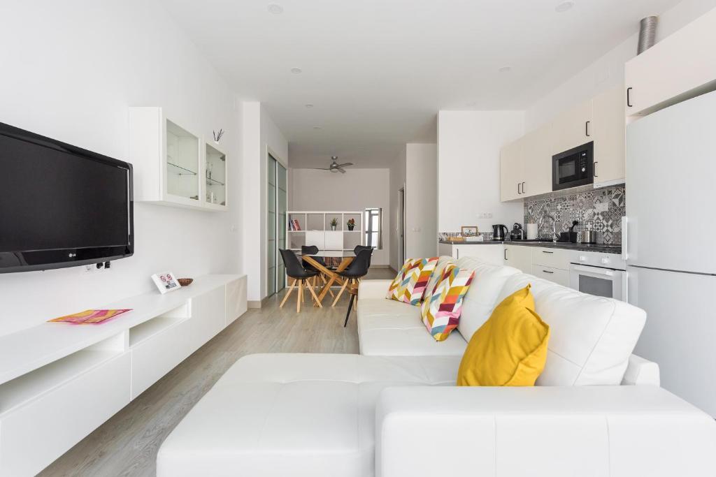 a white living room with a white couch and a kitchen at Charming Loft A in Málaga