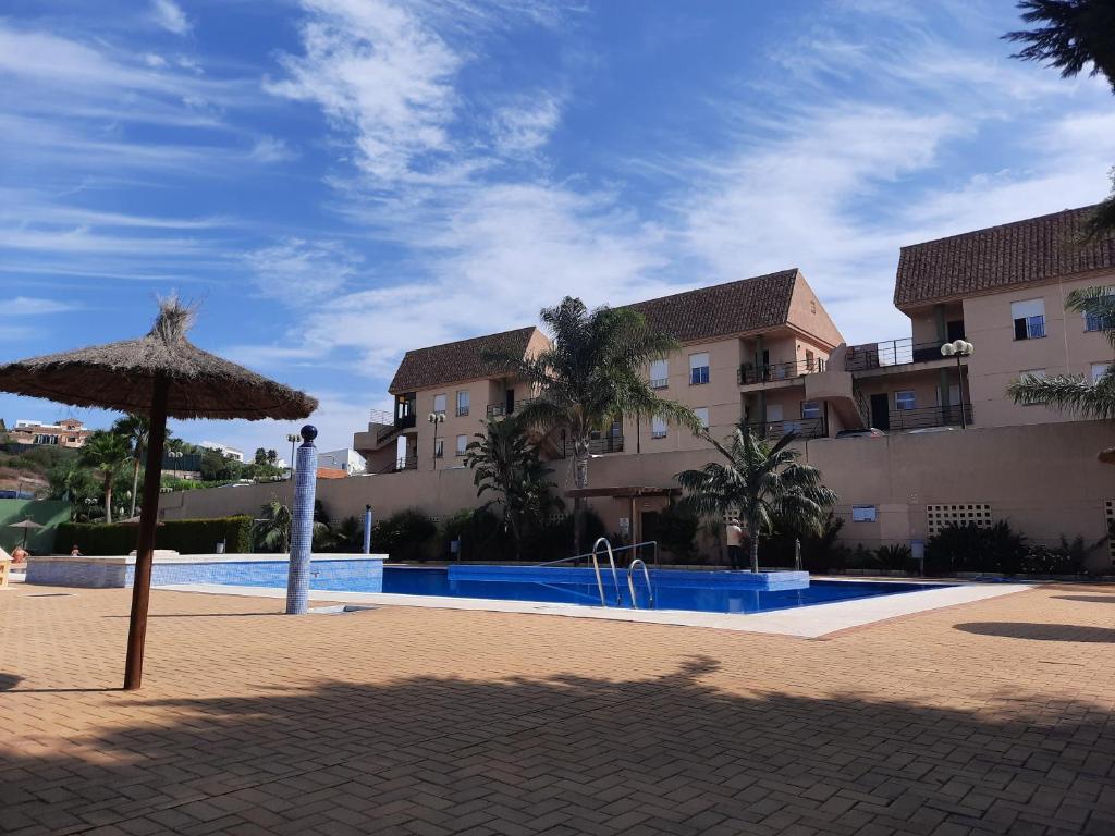a swimming pool with an umbrella next to a building at Estudio Regency Alcaidesa in La Alcaidesa