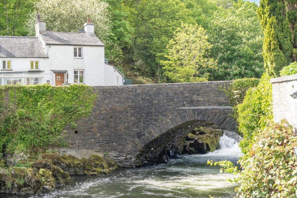 a stone bridge over a river with a house at Bridge House in Ulverston