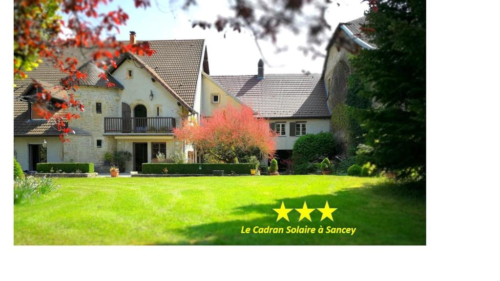 a house with a yard with green grass and yellow stars at Doubs Le Cadran Solaire, gite ROMANCE class 3 étoiles in Sancey-le-Grand