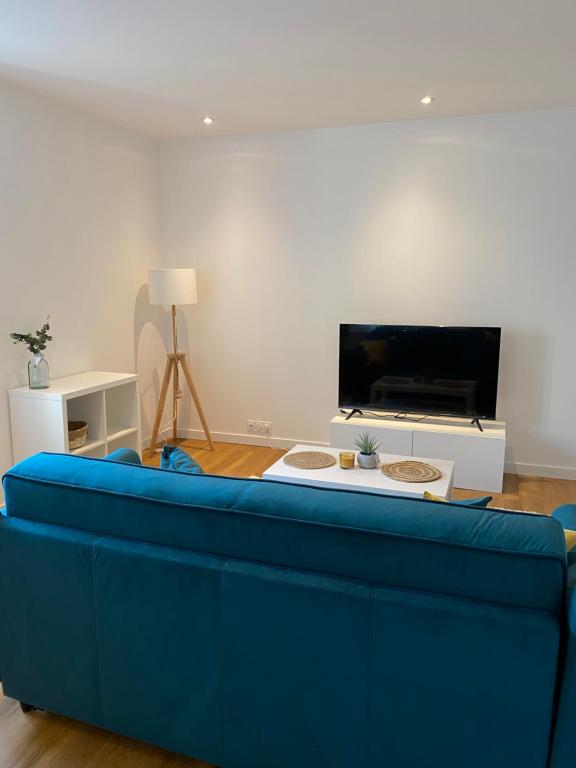 un divano blu in soggiorno con TV di Lorient: appartement élégant a Lorient