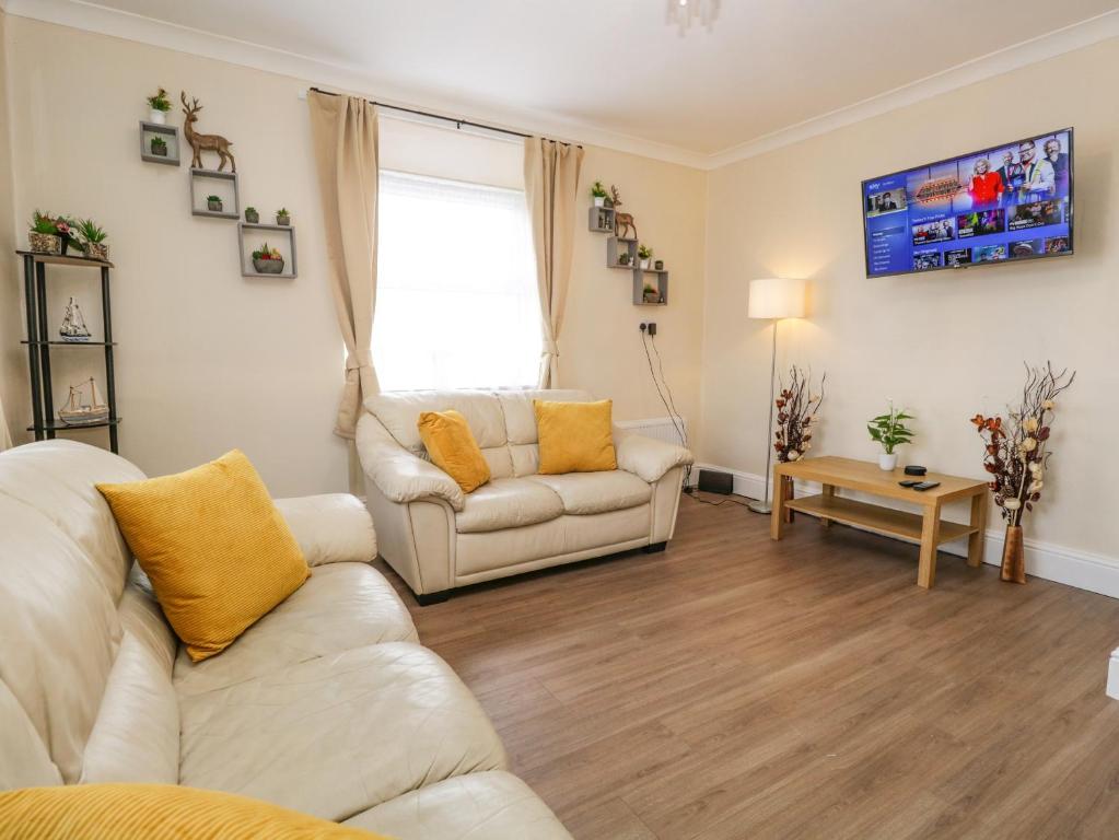 una sala de estar con 2 sofás blancos y una ventana en Neland View en Windermere