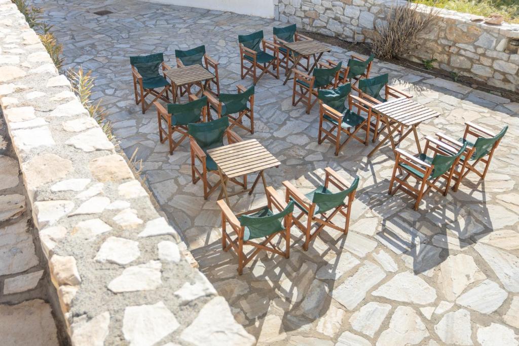 un grupo de mesas y sillas de madera en un patio de piedra en Akti Apollona, en Apollon