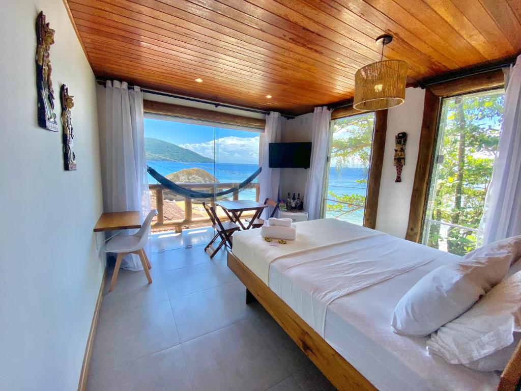 um quarto com uma cama e vista para o oceano em Pousada Belas Águas em Praia de Araçatiba