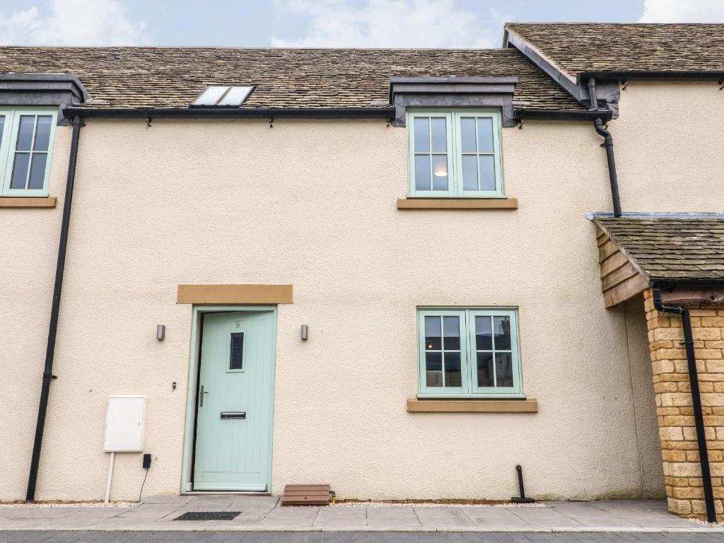 a brick house with a blue door and windows at 9 Windrush Heights in Burford