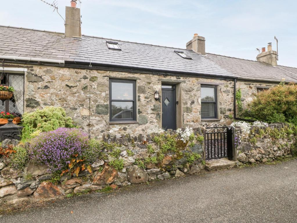 uma casa de pedra com flores em frente em 2 Rhoslyn em Caernarfon