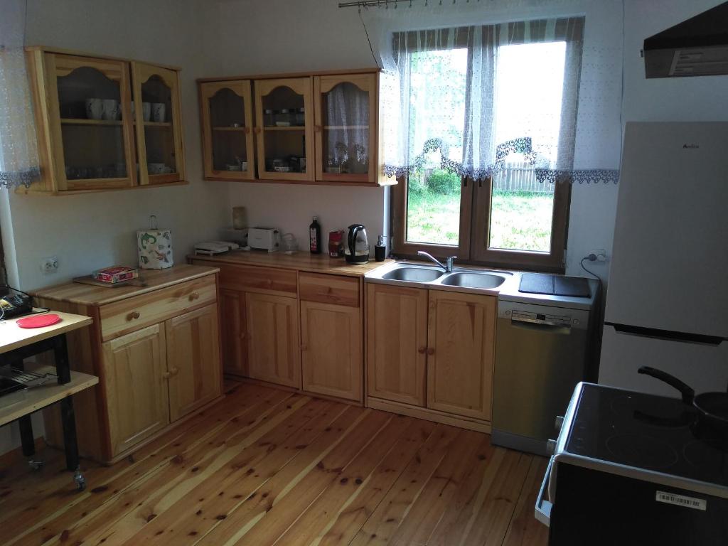 a kitchen with wooden cabinets and a wooden floor at dom drewniany pod lasem in Zatory