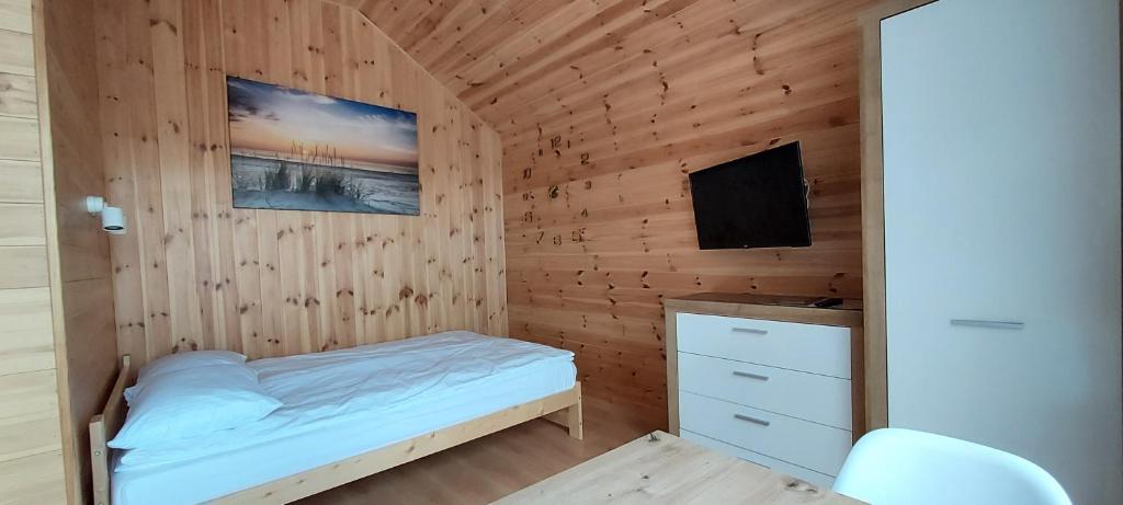 małą sypialnię z łóżkiem i telewizorem w obiekcie Gemini MiniDomki w Ustce