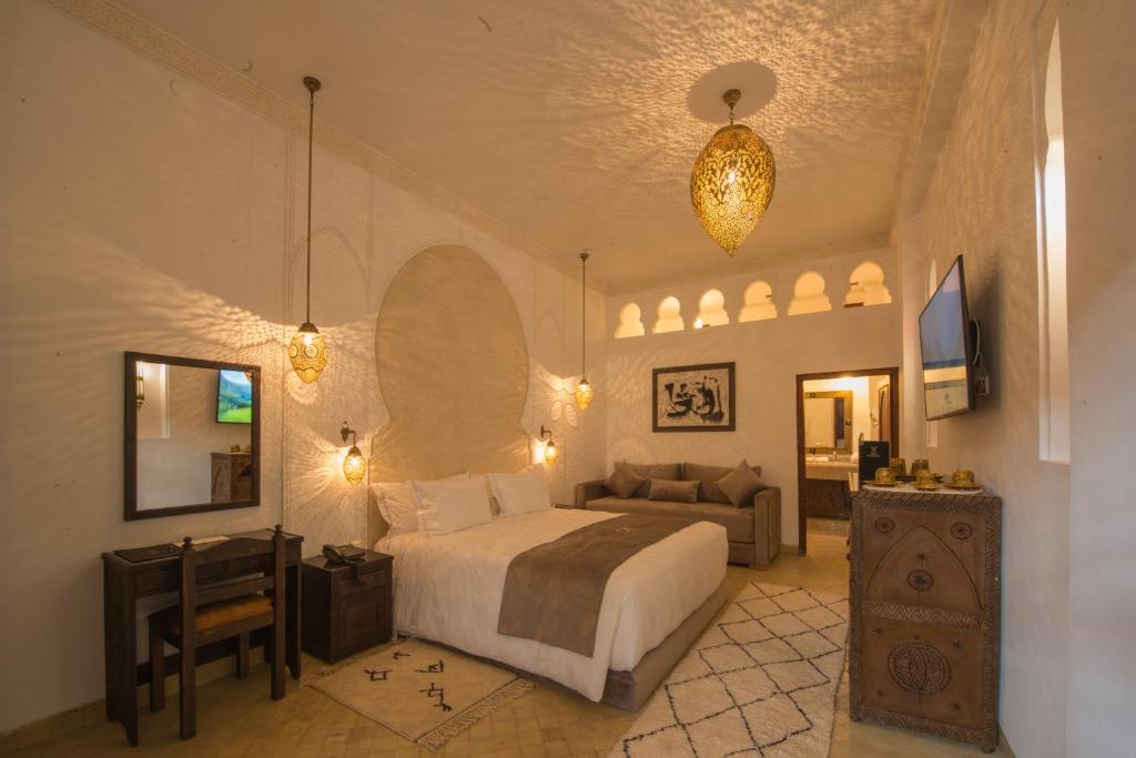 Riad la clé d'or & spa في مراكش: غرفة نوم بسرير واريكة في غرفة