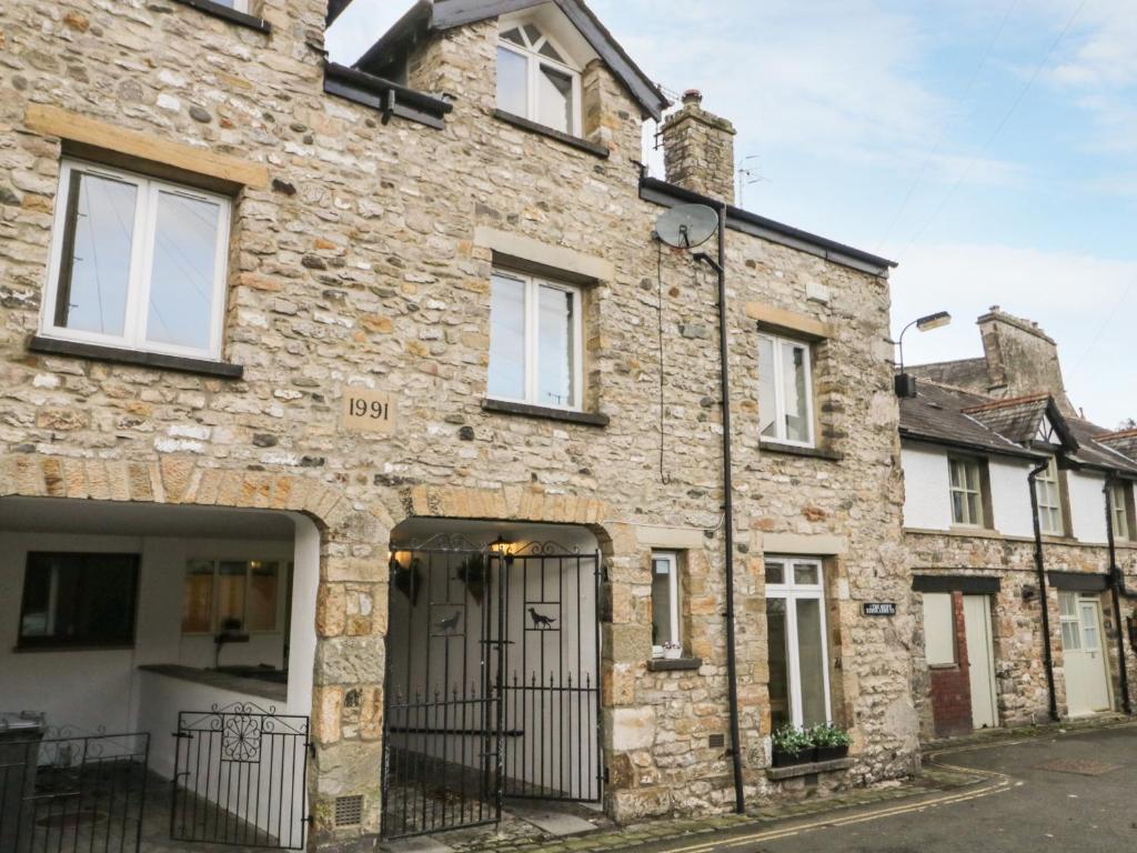 an old stone house with a gate on a street at Kirkby House in Carnforth