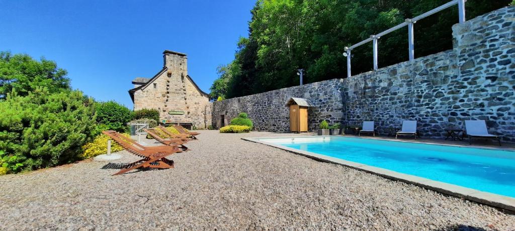 una casa con piscina y un edificio de piedra en Le Mas de Rigoulac chambre Zen SPA sur réservation, en Bouyssounouse